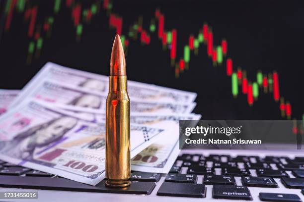 rifle bullet on keyboard with stock chart going down background. - bidding war stock pictures, royalty-free photos & images