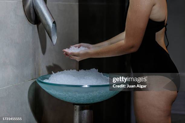 a woman collects ice before entering the sauna. - cryotherapy stockfoto's en -beelden