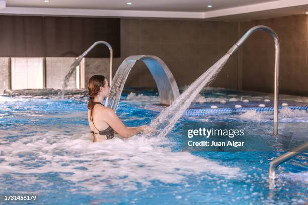 young woman in a spa pool in front of the hydromassage jet. - algar waterfall spain stock pictures, royalty-free photos & images