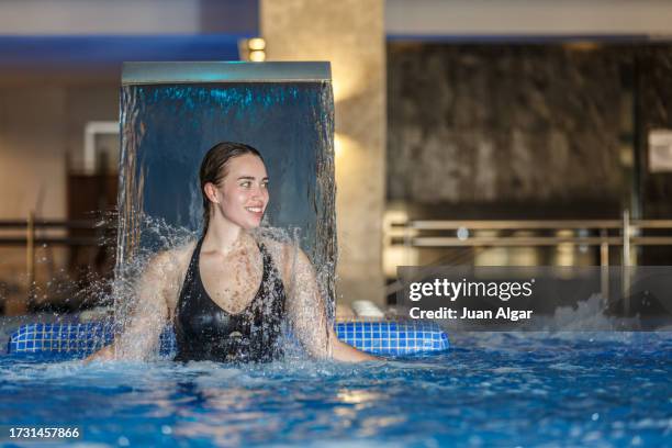 young woman smiling in a spa pool under a hydromassage waterfall - algar waterfall spain stock pictures, royalty-free photos & images