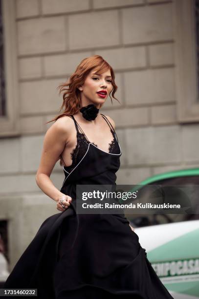 Jordanna Maia wears black heels, a black silk dress, a black bag, a black lace bra, and a choker decorated with a black flower outside Philosophy di...