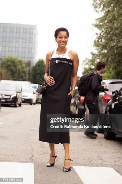 Tamu McPherson wears a white top, long black strapless dress with a belt, high heels, and black Chanel bag outside Sportmax during the Milan Fashion...