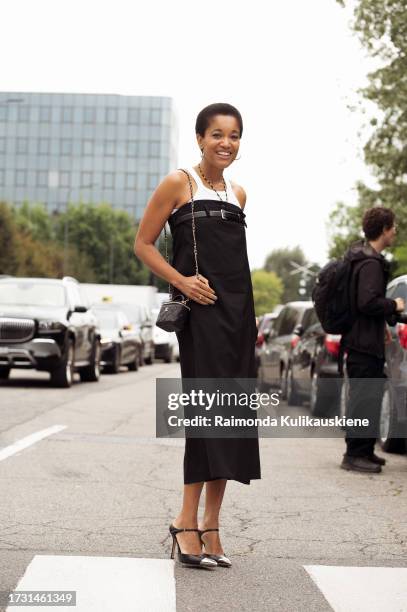 Tamu McPherson wears a white top, long black strapless dress with a belt, high heels, and black Chanel bag outside Sportmax during the Milan Fashion...