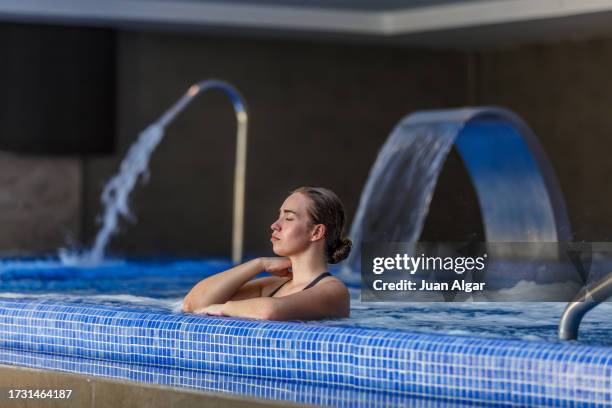 young woman with eyes closed relaxing in the hydrotherapy pool of a spa - établissement de cure photos et images de collection