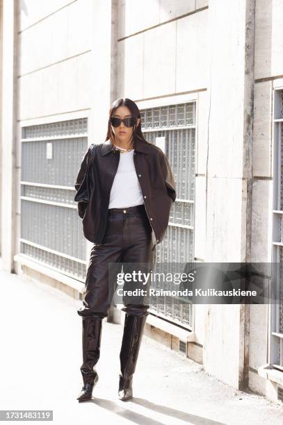 Yuwei Zhangzou wears a black leather pants, a white tank top, a black leather jacket, black shoes and sunglasses outside Bally during the Milan...