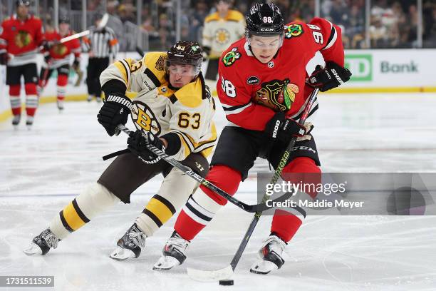 Brad Marchand of the Boston Bruins and Connor Bedard of the Chicago Blackhawks battle for control of the puck during the third period of the Bruins...