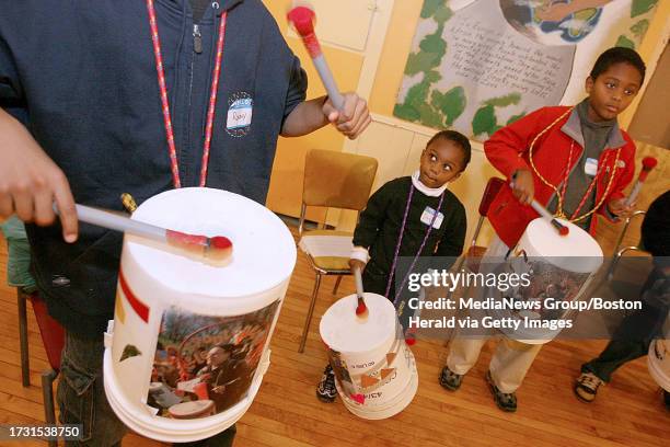 Four-year-old Davin Pandian of Newton looks up at an older drummer as he and his brother, Dinéh, right, practice with a junk percussion group for...