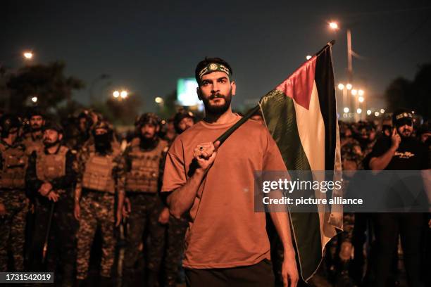 October 2023, Iraq, Baghdad: A protester holds a during a Palestinian flag during a protest to support the Palestinian people and protest against the...