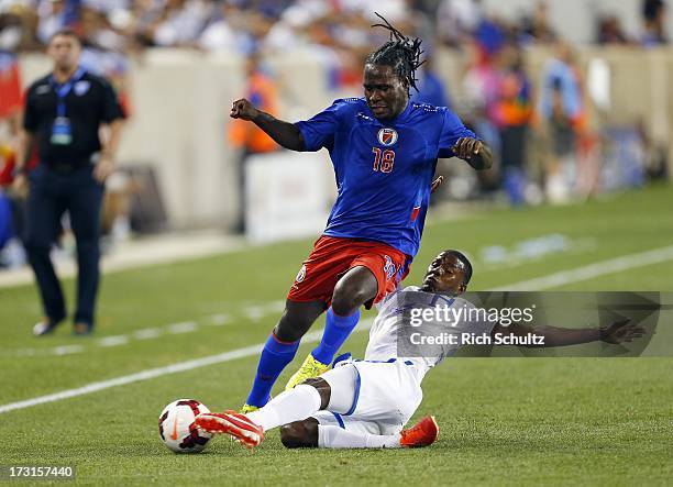 Defender Juan Carlos Garcia of Honduras makes a slid tackle on a ball controlled by forward Leonel Saint Preux of Haiti during the first half of a...