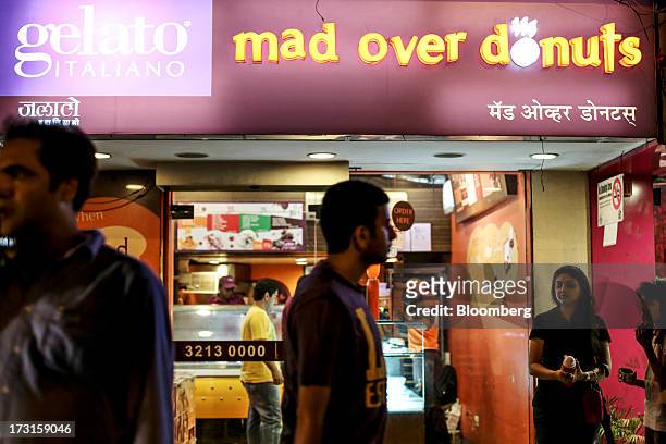 Pedestrains walk past a Gelato Italiano ice cream and Mad Over Donuts store in the suburb of Bandra in Mumbai, India, on Saturday, July 6, 2013....