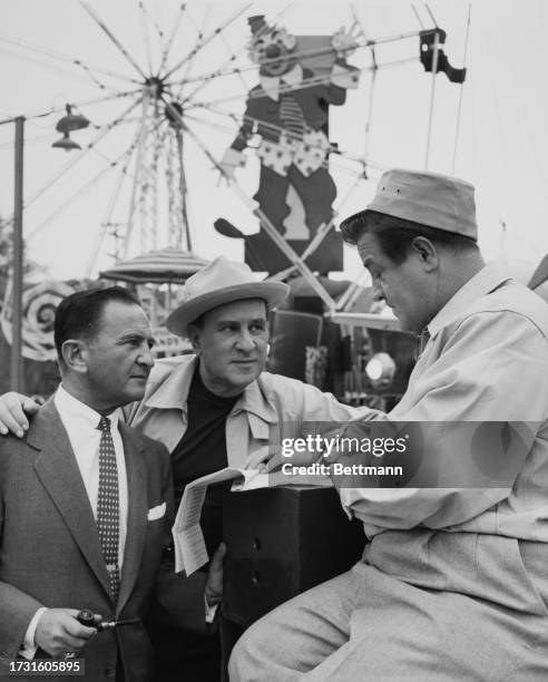 Comedy duo Bud Abbott and Lou Costello sign a new contract with their manager Eddie Sherman on the amusement park set of their new film 'Dance With...