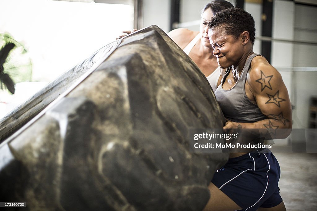 Women doing tire-flip exercise