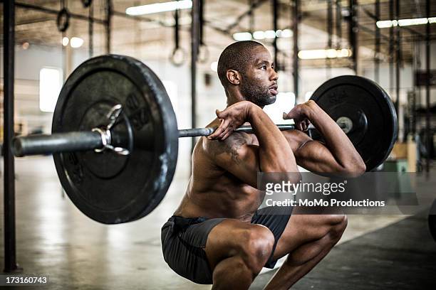 man doing gym/ front squat - squatting position - fotografias e filmes do acervo