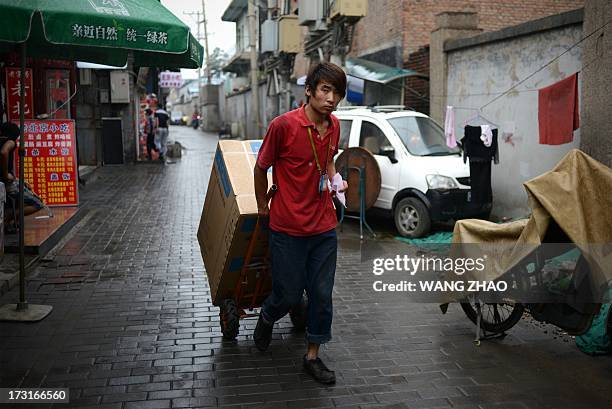 Man pulls goods on a trolley outside a restaurant at a alley in Beijing on July 9, 2013. China's annual inflation accelerated to 2.7 percent in June,...