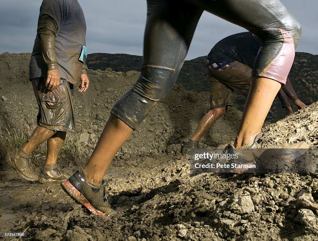 Legs and feet climbing up mud obstacle.