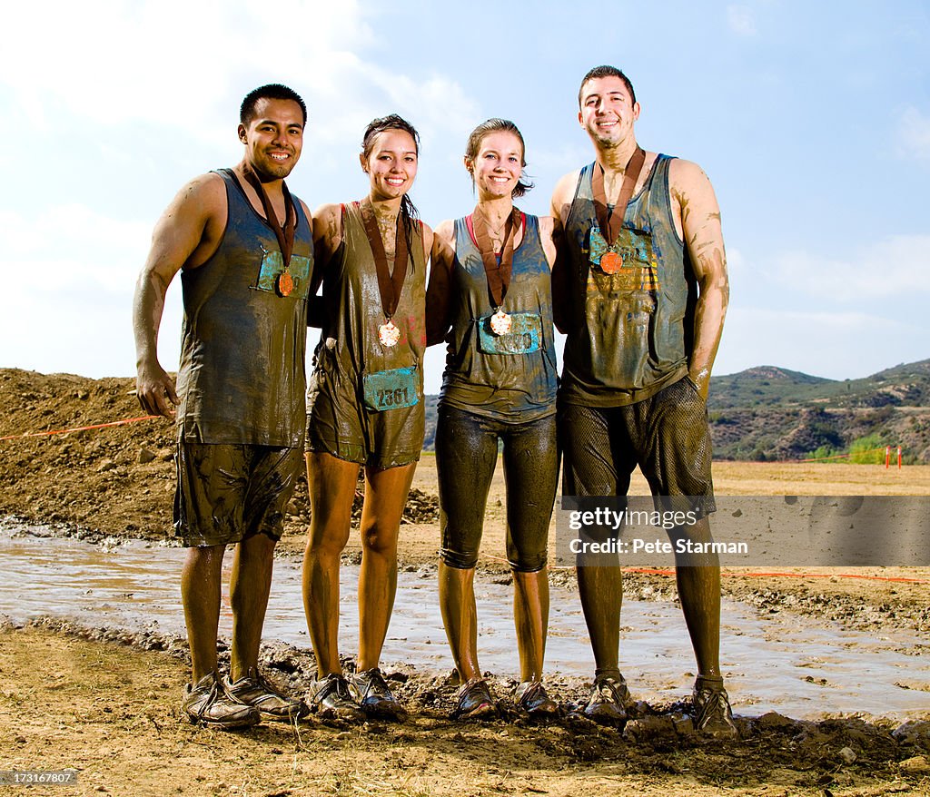 Four friends competing in a mud run(18-25) yrs.