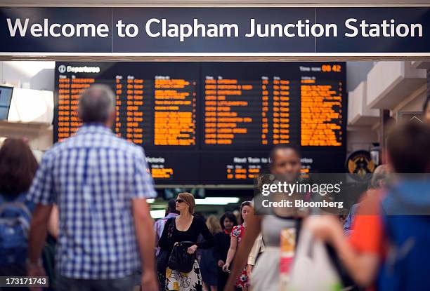 Commuters and rail travelers walk beneath a sign inside Clapham Junction train station in London, U.K., on Tuesday, July 9, 2013. U.K. Prime Minister...