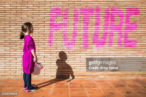 young girl empowered protesting and painting the future word on a brick wall. - earth rights imagens e fotografias de stock