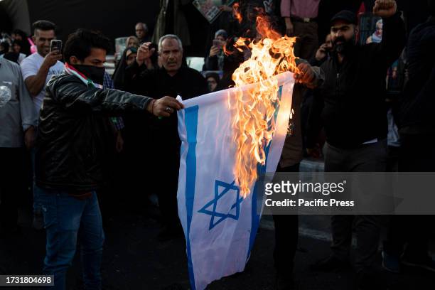 Iranian protestors burn an Israeli flag during an anti-Israel rally at Enqelab-e-Eslami Square.