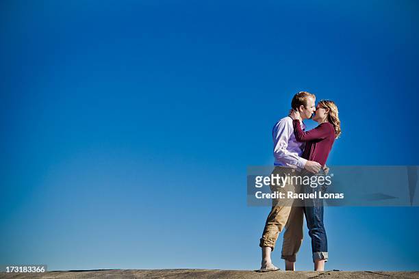young blond couple standing and kissing - young woman standing against clear sky ストックフォトと画像