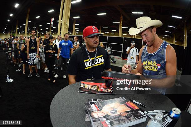 Donald "Cowboy" Cerrone signs autographs for fans during day one of the UFC Fan Expo Las Vegas 2013 at the Mandalay Bay Convention Center on July 5,...