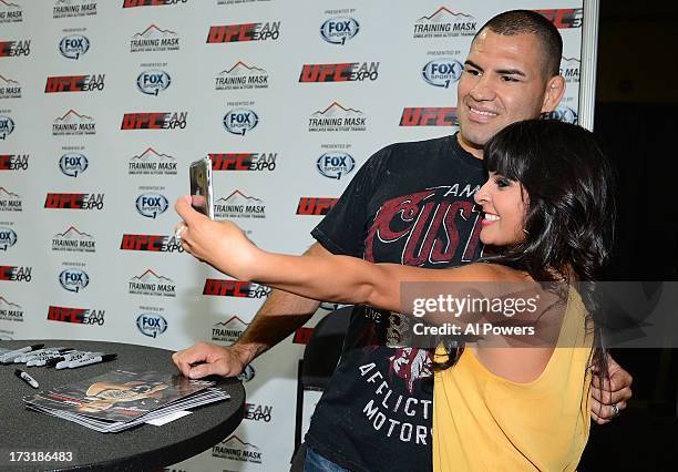 Heavyweight champion Cain Velasquez poses for a photo with a fan during day one of the UFC Fan Expo Las Vegas 2013 at the Mandalay Bay Convention...