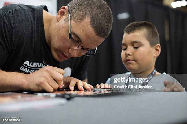 Heavyweight Pat Barry signs an autograph for a young fan during day one of the UFC Fan Expo Las Vegas 2013 at the Mandalay Bay Convention Center on...