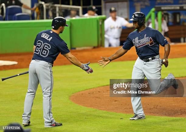 Justin Upton of the Atlanta Braves is congratulated by Dan Uggla after scoring during a game against the Miami Marlins at Marlins Park on July 9,...