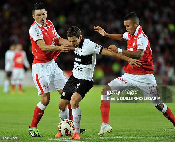 Colombian Independiente Santa Fe's players Daniel Torres and Francisco Meza vie for the ball with Enzo Prono of Paraguay's Olimpia during their 2013...