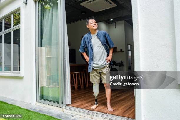 man with prosthetic leg standing at home - robotics alive stock pictures, royalty-free photos & images