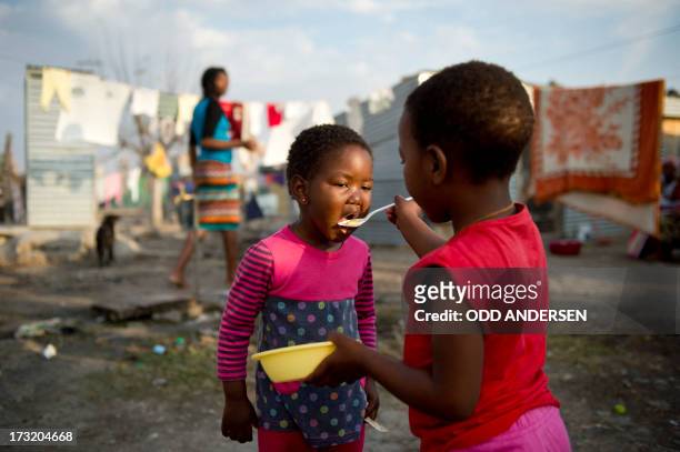 Girl feeds her sister on July 9, 2013 in the Nkaneng shantytown next to the platinum mine, run by British company Lonmin, in Marikana. On August 16...