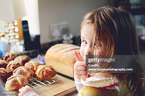 little girl licking fingers at easter - sweet bun stockfoto's en -beelden