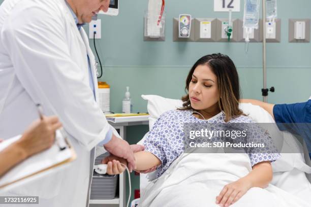 female patient watches while the male physician examines her arm - bedside manner stock pictures, royalty-free photos & images