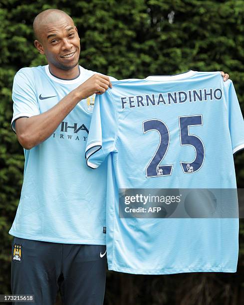 Manchester City's newly-signed Brazilian midfielder Fernandinho holds the Manchester City team players' shirt during a press photocall at their...