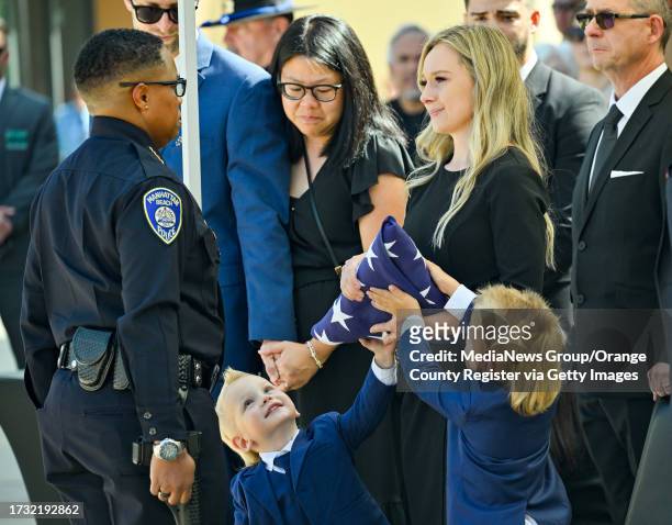 Cypress, CA Hailey Swanson, with her sons, receives a flag from Manhattan Beach Police Chief Rachel Johnson, during her husband's funeral at SeaCoast...