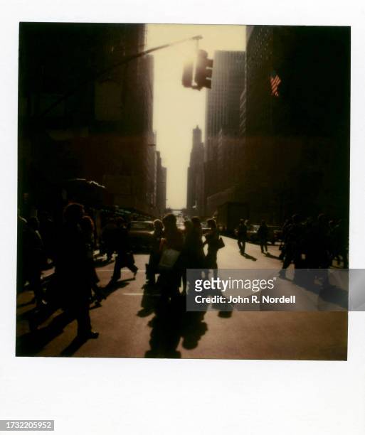 Polaroid photo of people crossing the street in the shadows of buildings in New York, New York, circa 1978.