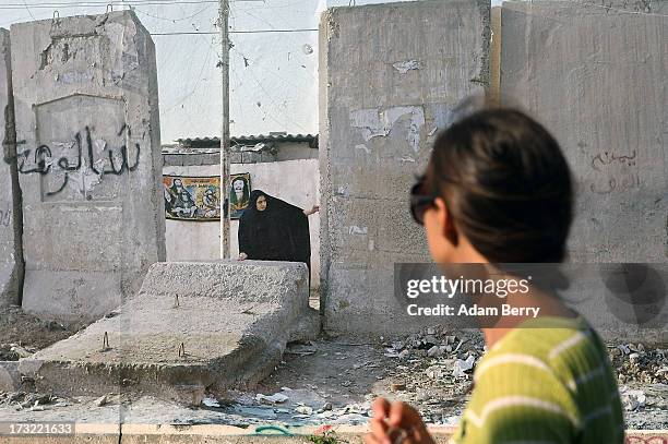 Visitor looks at a photo of a separation wall in Sadr City, Baghdad, Iraq as it hangs as part of the 'Wall on Wall' exhibition at the East Side...