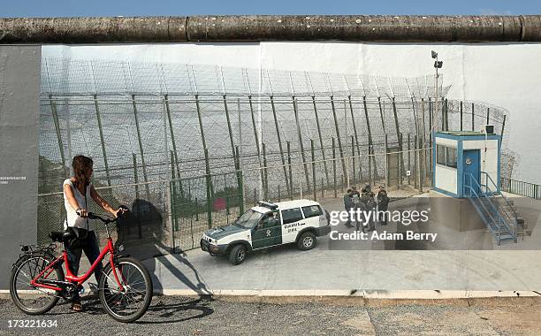 Visitor looks at a photo of the border between Ceuta and Melilla, Spain and Morocco as it hangs as part of the 'Wall on Wall' exhibition at the East...