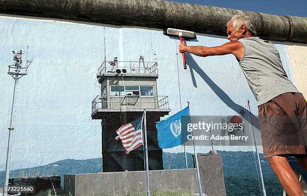 Worker hangs a photo of the North and South Korean border's Demilitarized Zone as part of the 'Wall on Wall' exhibition at the East Side Gallery...