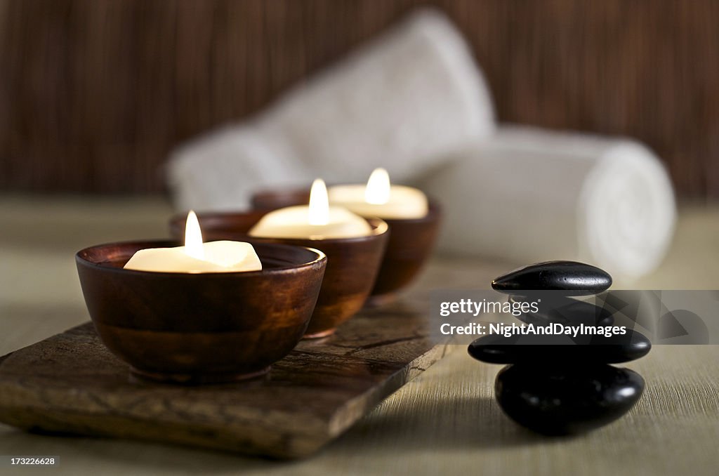 Lit candles and black massage stones in Zen spa