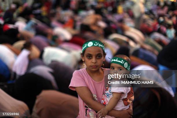 An Egyptian girl holds a baby as Egyptian supporters of the Muslim Brotherhood and Egypt's ousted president Mohamed Morsi pray outside Cairo's Rabaa...