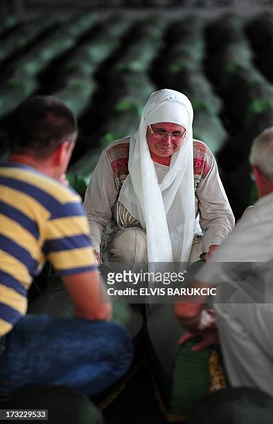 Bosnian Muslim woman, survivor of Srebrenica 1995 massacre, mourns near body caskets of her relatives, layed out in a factory hangar, near memorial...