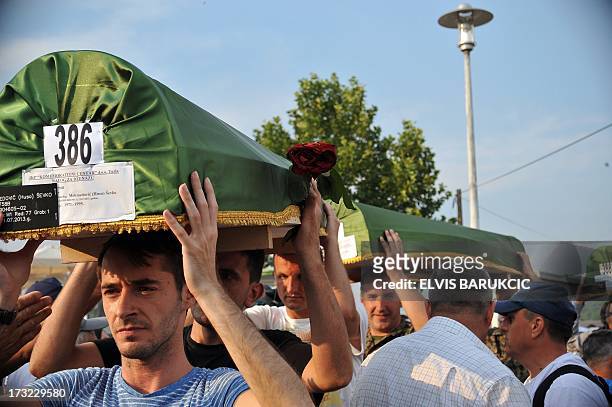Bosnian Muslims, survivors of Srebrenica 1995 massacre, carry body caskets of their relatives, from a factory hangar, near memorial cemetery in...