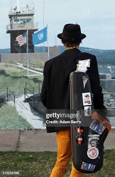 Saxophone player looks at a photo of the North and South Korean border's Demilitarized Zone as part of the 'Wall on Wall' exhibition at the East Side...