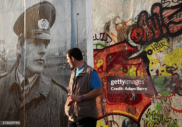 Visitor stands near a photo of a German Democratic Republic border guard at the former border between East and West Germany, hanging as part of the...