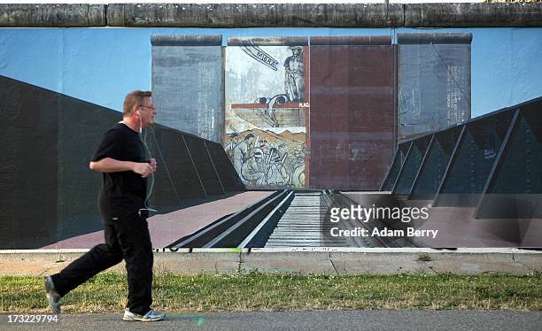 Jogger passes a photo of the United States-Mexico border in Ciudad Juarez, Mexico, hanging as part of the 'Wall on Wall' exhibition at the East Side...