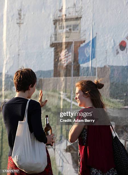 Visitors look at a photo of the North and South Korean border's Demilitarized Zone as part of the 'Wall on Wall' exhibition at the East Side Gallery...