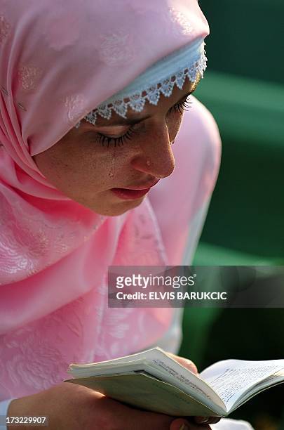 Bosnian Muslim woman, survivor of Srebrenica 1995 massacre, reads a prayer over body casket of her relative, at memorial cemetery in village of...