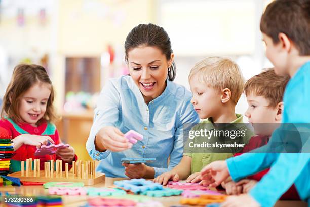 kindergarten lehrer spielen mit kindern - puériculture stock-fotos und bilder