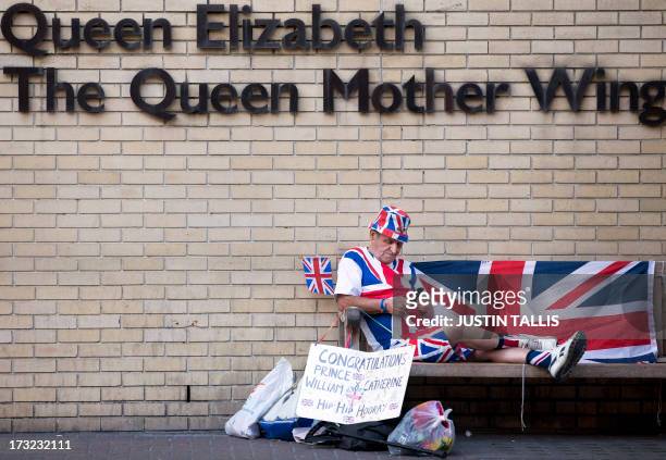 Royal supporter Terry Hutt sits on a bench looking at his mobile phone in front of the Queen Elizabeth, The Queen Mother Wing, directly opposite The...